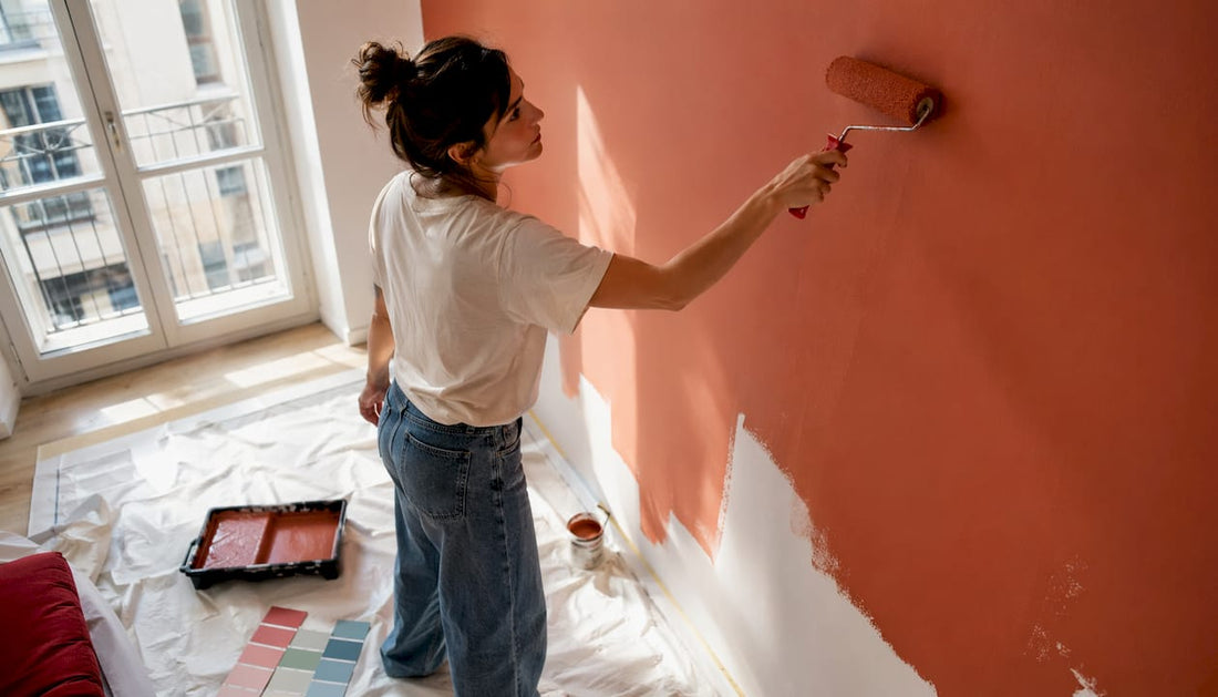 Una donna sta tinteggiando una parete di casa con una vivace tonalità di verde.