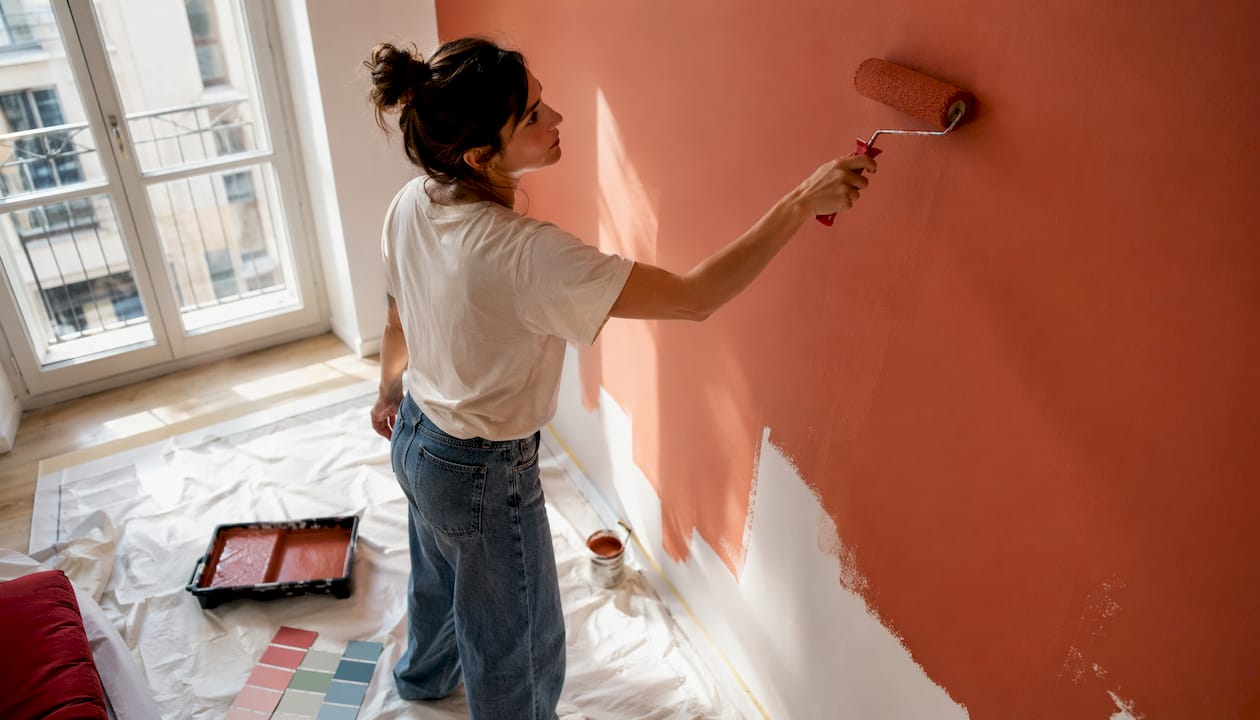 Una donna sta tinteggiando una parete di casa con una vivace tonalità di verde.