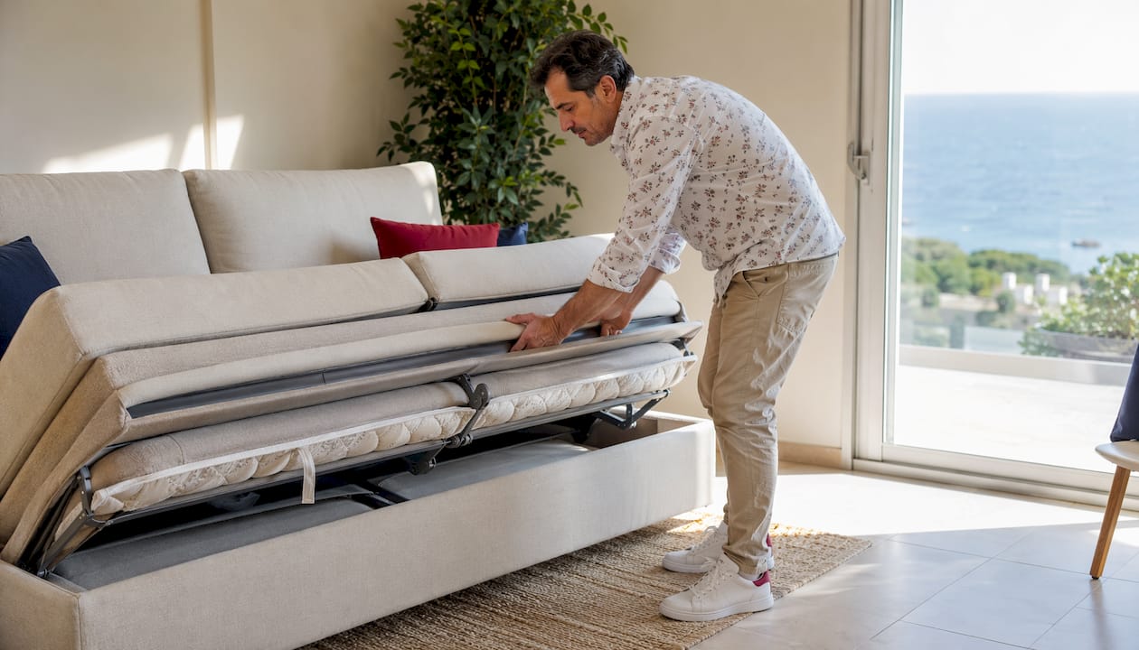 Un uomo apre il divano letto multifunzione in salotto.