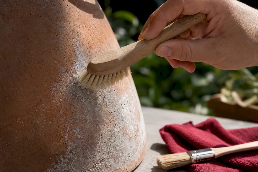 Una mano pulisce la patina bianca dalla terracotta